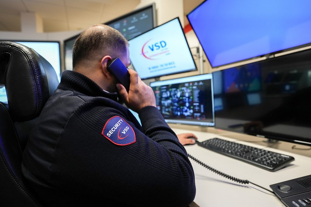 VSD Security-Mitarbeiter in der Notruf- und Serviceleitstelle beim Telefoneinsatz vor Überwachungsmonitoren mit Alarmmanagement-Software